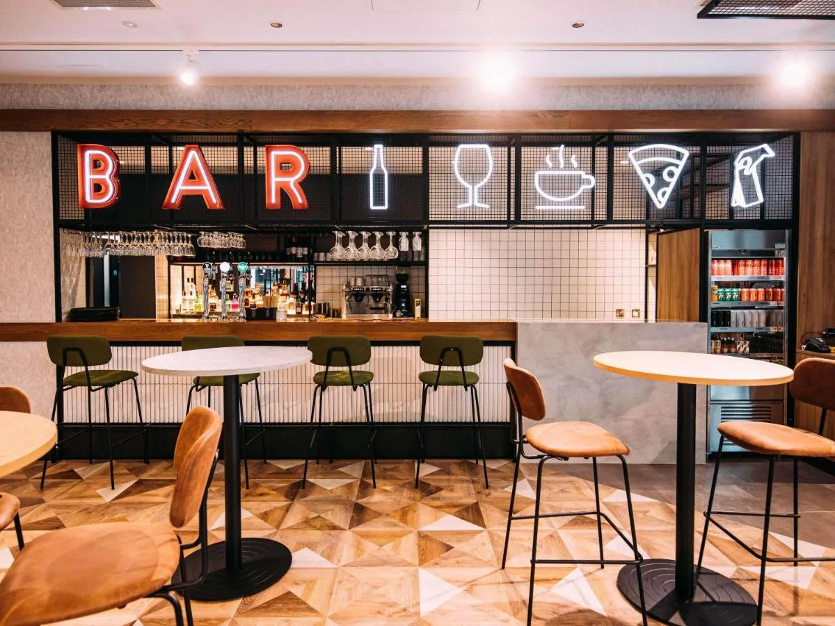 a bar with tables and chairs in a restaurant at ibis Belfast City Centre in Belfast