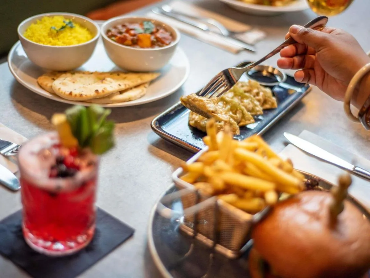 a table with plates of food and a drink and french fries at ibis Belfast City Centre in Belfast